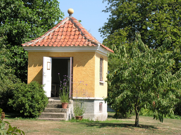 historisches, gelbgetünchtes Gärtnerhäuschen in parkähnlichem Garten